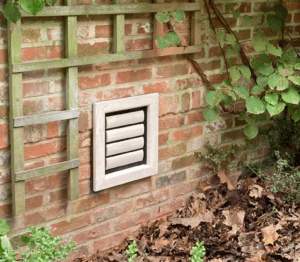 Chatière et trappe pour chien en bois pour chats et petits chiens installées par Tomsgates dans un mur de jardin en pierre rustique, en bois vieilli et envahi par les plantes.