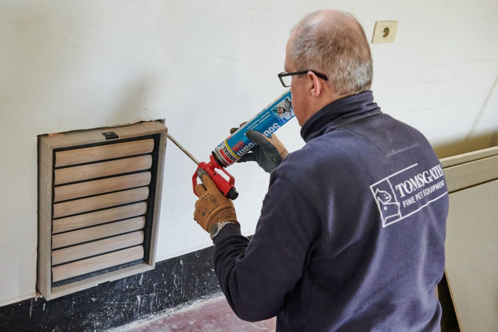 Groot hondenluik in stenen muur plaatsen door installateur van Tomsgates